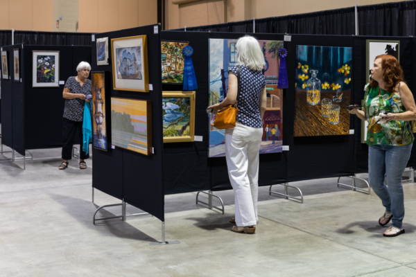 women looking at paintings displayed on screens